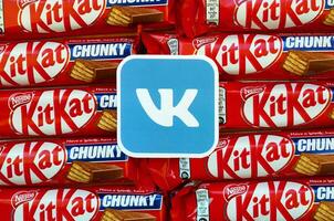 Vkontakte paper logo on many Kit Kat chocolate covered wafer bars in red wrapping. Advertising chocolate product in Vkontakte social network and world wide web photo
