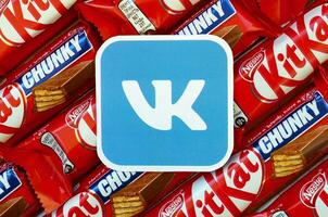 Vkontakte paper logo on many Kit Kat chocolate covered wafer bars in red wrapping. Advertising chocolate product in Vkontakte social network and world wide web photo
