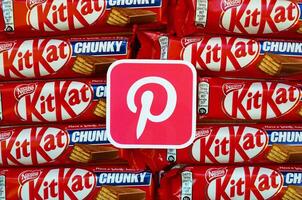 Pinterest paper logo on many Kit Kat chocolate covered wafer bars in red wrapping. Advertising chocolate product in Pinterest social network and world wide web photo