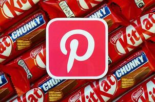 Pinterest paper logo on many Kit Kat chocolate covered wafer bars in red wrapping. Advertising chocolate product in Pinterest social network and world wide web photo