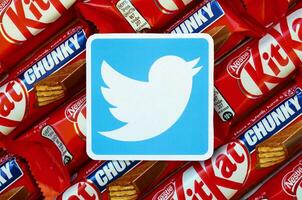 Twitter paper logo on many Kit Kat chocolate covered wafer bars in red wrapping. Advertising chocolate product in Twitter social network and world wide web photo