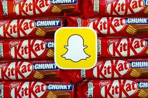 Snapchat paper logo on many Kit Kat chocolate covered wafer bars in red wrapping. Advertising chocolate product in Snapchat social network and world wide web photo