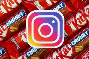 Instagram paper logo on many Kit Kat chocolate covered wafer bars in red wrapping. Advertising chocolate product in Instagram social network and world wide web photo