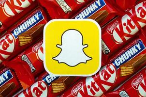 Snapchat paper logo on many Kit Kat chocolate covered wafer bars in red wrapping. Advertising chocolate product in Snapchat social network and world wide web photo