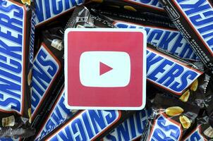 Youtube paper logo on many Snickers chocolate covered wafer bars in brown wrapping. Advertising chocolate product in Youtube social network and world wide web photo