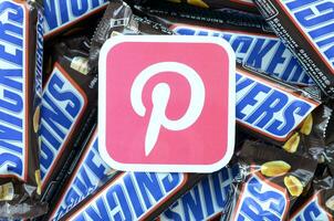 Pinterest paper logo on many Snickers chocolate covered wafer bars in brown wrapping. Advertising chocolate product in Pinterest social network and world wide web photo