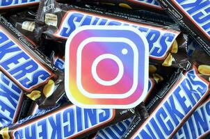 Instagram paper logo on many Snickers chocolate covered wafer bars in brown wrapping. Advertising chocolate product in Instagram social network and world wide web photo