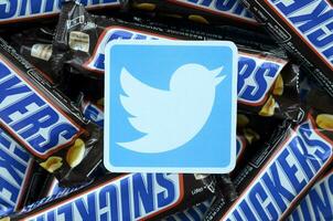 Twitter paper logo on many Snickers chocolate covered wafer bars in brown wrapping. Advertising chocolate product in Twitter social network and world wide web photo