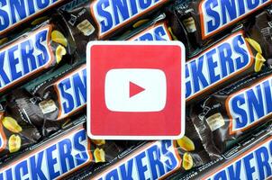 Youtube paper logo on many Snickers chocolate covered wafer bars in brown wrapping. Advertising chocolate product in Youtube social network and world wide web photo