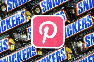 Pinterest paper logo on many Snickers chocolate covered wafer bars in brown wrapping. Advertising chocolate product in Pinterest social network and world wide web photo