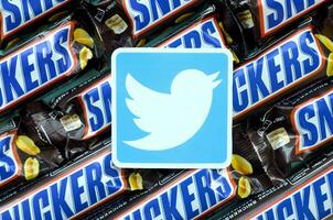 Twitter paper logo on many Snickers chocolate covered wafer bars in brown wrapping. Advertising chocolate product in Twitter social network and world wide web photo