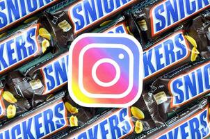 Instagram paper logo on many Snickers chocolate covered wafer bars in brown wrapping. Advertising chocolate product in Instagram social network and world wide web photo