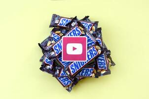 Youtube paper logo on many Snickers chocolate covered wafer bars in brown wrapping. Advertising chocolate product in Youtube social network and world wide web photo