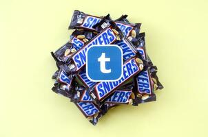 Tumblr paper logo on many Snickers chocolate covered wafer bars in brown wrapping. Advertising chocolate product in Tumblr social network and world wide web photo