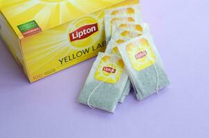 Lipton Yellow Label black tea pack and teabags on pastel lilac surface close up. Lipton is a world famous brand of tea photo