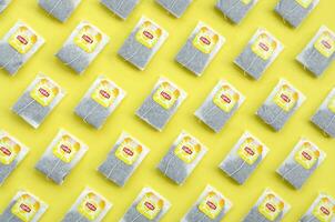 Flat lay of Lipton Yellow Label black tea bags on pastel yellow surface. Lipton is a world famous brand of tea photo