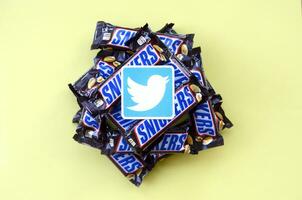 Twitter paper logo on many Snickers chocolate covered wafer bars in brown wrapping. Advertising chocolate product in Twitter social network and world wide web photo