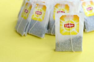Lipton Yellow Label black tea bags on pastel yellow surface close up. Lipton is a world famous brand of tea photo