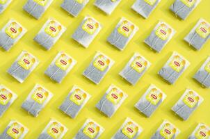 Flat lay of Lipton Yellow Label black tea bags on pastel yellow surface. Lipton is a world famous brand of tea photo