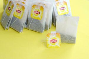 Lipton Yellow Label black tea bags on pastel yellow surface close up. Lipton is a world famous brand of tea photo