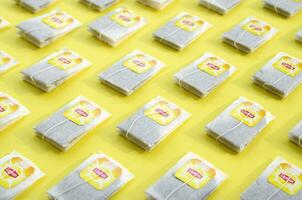 Flat lay of Lipton Yellow Label black tea bags on pastel yellow surface. Lipton is a world famous brand of tea photo