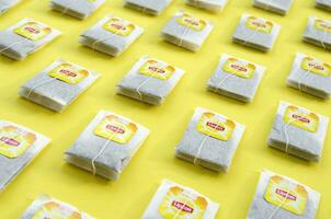 Flat lay of Lipton Yellow Label black tea bags on pastel yellow surface. Lipton is a world famous brand of tea photo