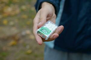 KHARKOV, UKRAINE - OCTOBER 26, 2019 Young man takes tic tac package to girl in autumn park. Tic tac is popular due its minty fresh taste by Ferrero photo