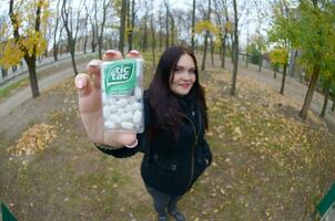 KHARKOV, UKRAINE - OCTOBER 26, 2019 Young woman shows new Tic tac hard mints package in autumn park. Tic tac is popular due its minty fresh taste by Ferrero photo