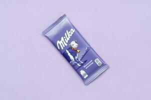 Milka chocolate tablet in classic violet wrapping on lilac background. Milka is brand of chocolate confection originated in Switzerland in 1901 photo