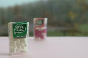 Many Tic Tac Candy packages on green wood background. Tic tac is popular due its minty fresh taste and easy to carry. Hard mints produced by Ferrero since 1968 photo