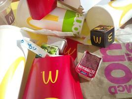 Used paper wrappings and disposable packs with McDonalds design and logo in pile on table. McDonalds recycle trash after usage photo