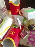 Used paper wrappings and disposable packs with McDonalds design and logo in pile on table. McDonalds recycle trash after usage photo