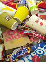 Many used food wrappings and drink cans by random food manufacturing famous brands. Recycled trash of treats and soda drinks photo