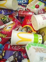 Many used food wrappings and drink cans by random food manufacturing famous brands. Recycled trash of treats and soda drinks photo