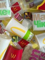 Used paper wrappings and disposable packs with McDonalds design and logo in pile on table. McDonalds recycle trash after usage photo