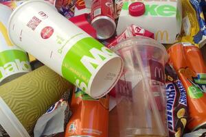 Many used food wrappings and drink cans by random food manufacturing famous brands. Recycled trash of treats and soda drinks photo