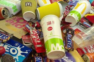 Many used food wrappings and drink cans by random food manufacturing famous brands. Recycled trash of treats and soda drinks photo