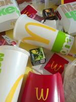 Used paper wrappings and disposable packs with McDonalds design and logo in pile on table. McDonalds recycle trash after usage photo