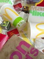 Used paper wrappings and disposable packs with McDonalds design and logo in pile on table. McDonalds recycle trash after usage photo