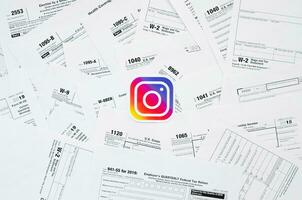 Printed Instagram logo on many tax form blanks lies on table close up. Help with tax problems using internet and information from social networks photo