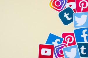 Many social network printed icons lies in pile on beige background with copy space. Facebook Instagram Pinterest Twitter Youtube Tumblr. Abstract internet background photo