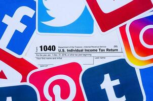 1040 U.S. Individual Income Tax Return form with printed logo of many social networks. Facebook Instagram Youtube Tumblr Twitter Pinterest photo