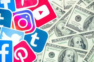 Many hundred dollars bills with printed logo of social networks. Facebook Instagram Youtube Tumblr Twitter Pinterest. Work using internet websites or apps photo