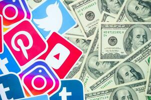 Many hundred dollars bills with printed logo of social networks. Facebook Instagram Youtube Tumblr Twitter Pinterest. Work using internet websites or apps photo