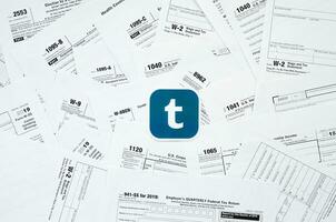 Printed Tumblr logo on many tax form blanks lies on table close up. Help with tax problems using internet and information from social networks photo