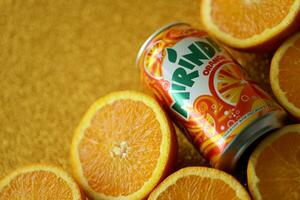 KYIV, UKRAINE - JULY 7, 2023 Mirinda orange drink with many oranges on colorful background photo