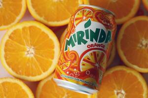 KYIV, UKRAINE - JULY 7, 2023 Mirinda orange drink with many oranges on colorful background photo