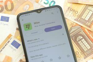 TERNOPIL, UKRAINE - AUGUST 3, 2023 Wise application on screen on modern smartphone and many bills of euro currency photo