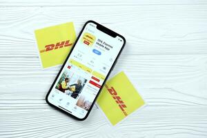 KHARKOV, UKRAINE - MARCH 5, 2021 DHL icon and application from App store on iPhone 12 pro display screen on white table photo