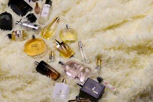 KHARKOV, UKRAINE - JANUARY 12, 2021 Many perfume bottles with famous brand names lies on fluffy beige plaid photo